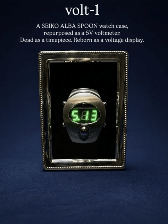Completed volt-1 in a silver frame, with a green voltage display visible through the salvaged watch opening.